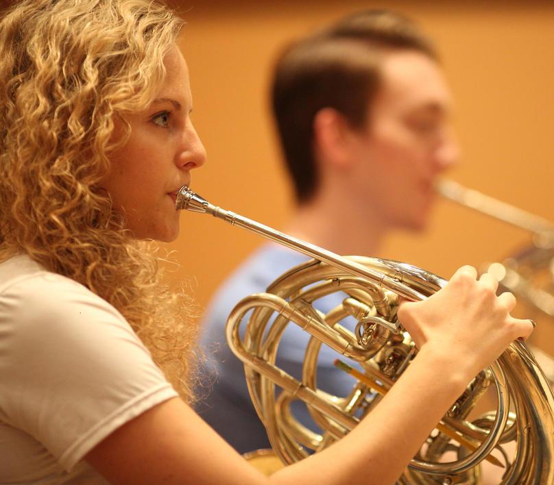 French Horn player in an orchestra rehearsal